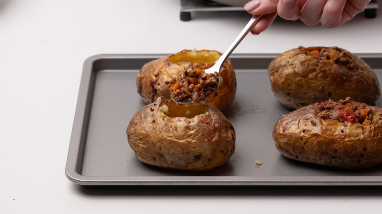 hand filling potato shells with mince