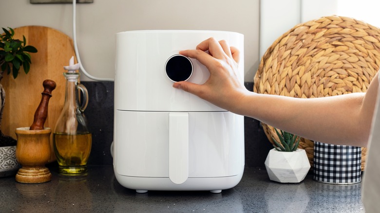 woman touching air fryer knob