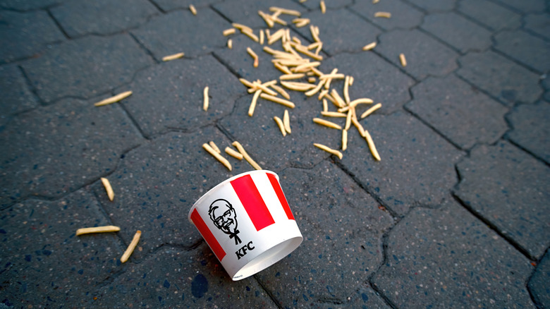 A KFC bucket and french fries on the ground