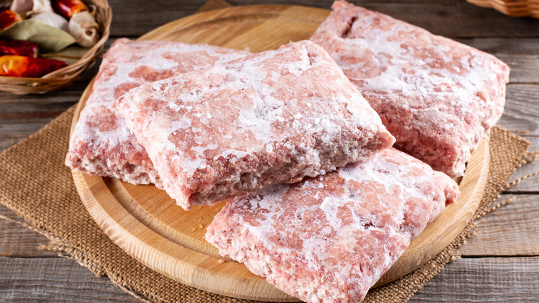 Chunks of frozen ground beef on a wooden board
