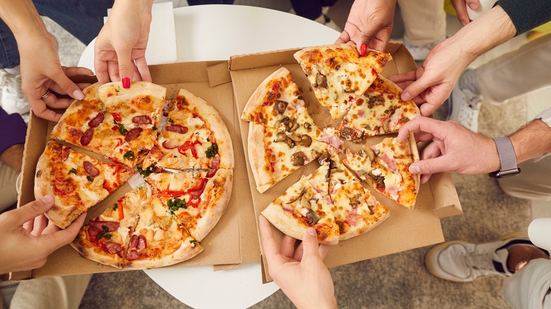 Hands grabbing takeout pizza slices