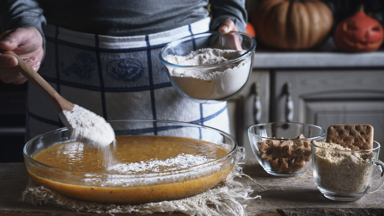 hand adding flour to batter