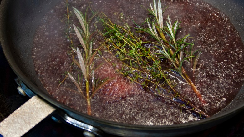 deglazing a pan with stock and herbs