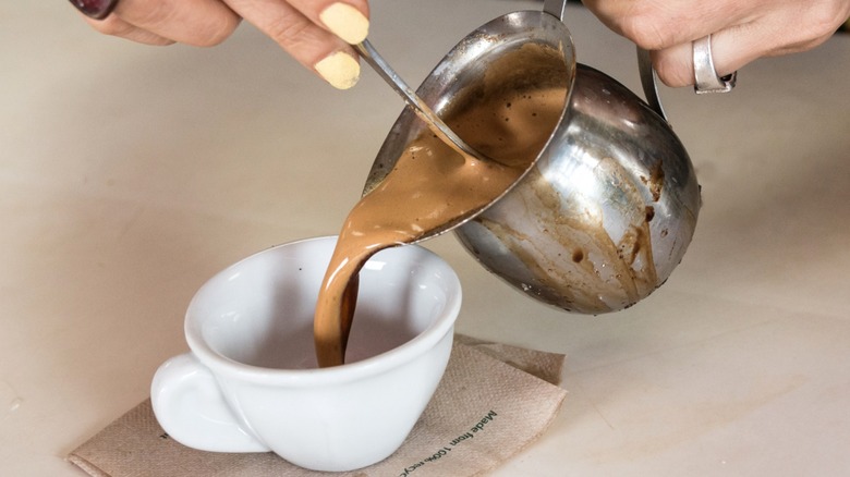 Hands pouring Cuban coffee into a mug