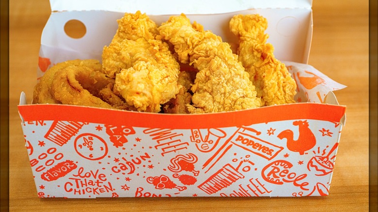 Popeyes fried chicken and onion rings in a to-go container