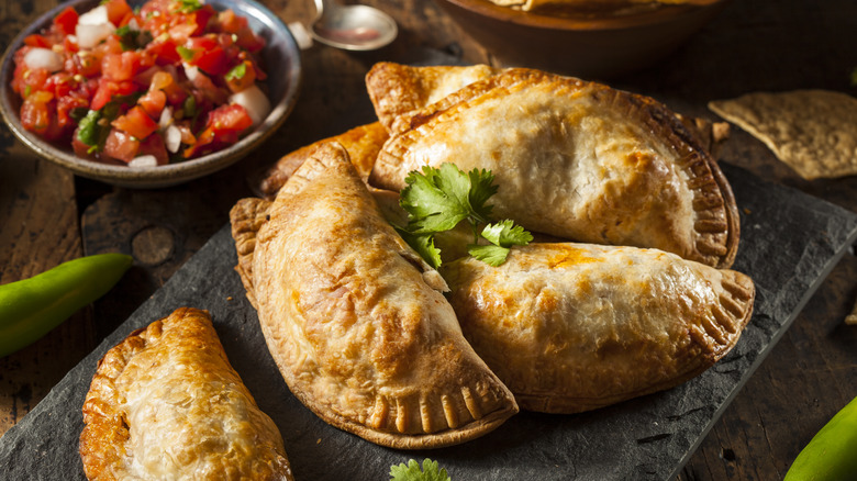 Empanadas on stone slab with cilantro garnish