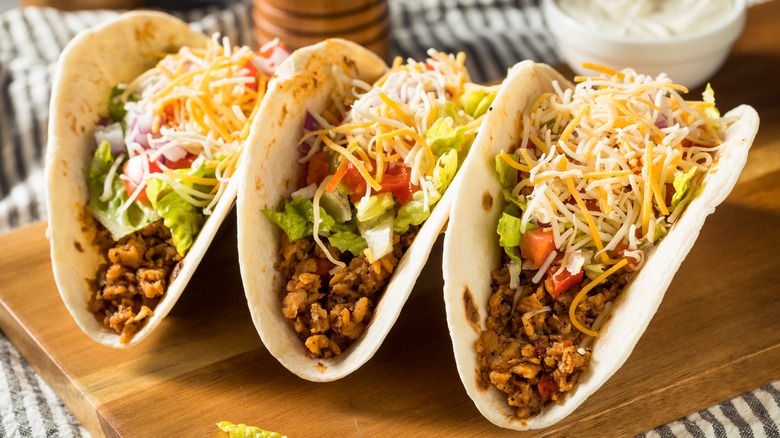 beef tacos in flour tortillas over a wood board