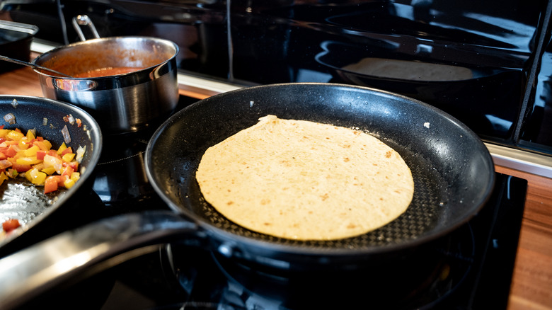 heating a tortilla in a sauce pan on the stove