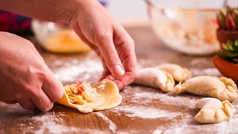 Hands folding empanadas 