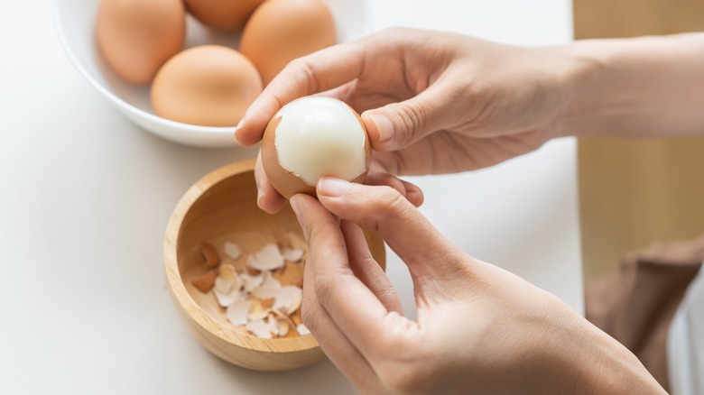 hands peeling boiled eggs