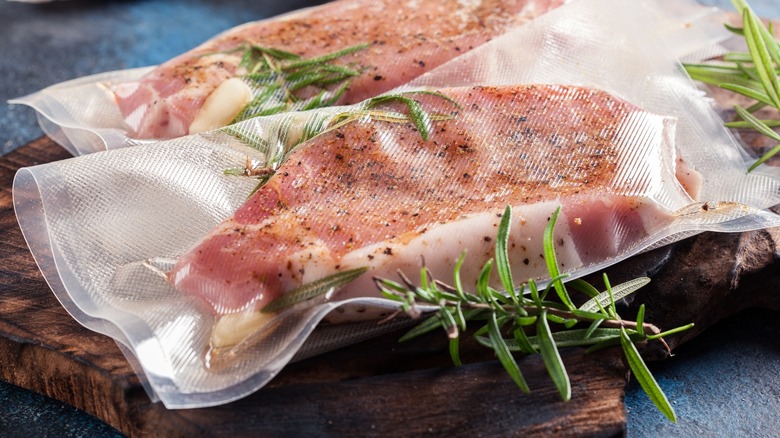 Close-up of sous vide pork in bags with rosemary and garlic