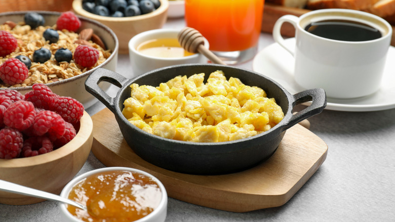 cast iron skillet with scrambled eggs surrounded by coffee, fruit, and granola