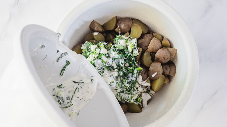 Pouring buttermilk ranch on baby potatoes