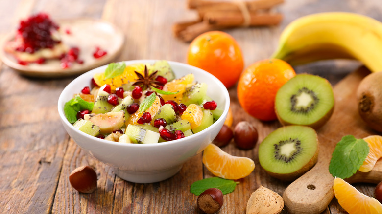 A bowl of fruit salad featuring kiwi, tangerines, and pomegranate