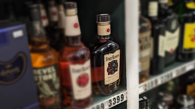 Four Roses Small Batch bourbon bottle on liquor store next to other whiskeys