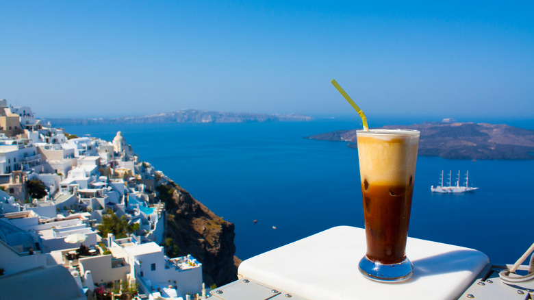 A freddo cappuccino sitting on a ledge overlooking blue water