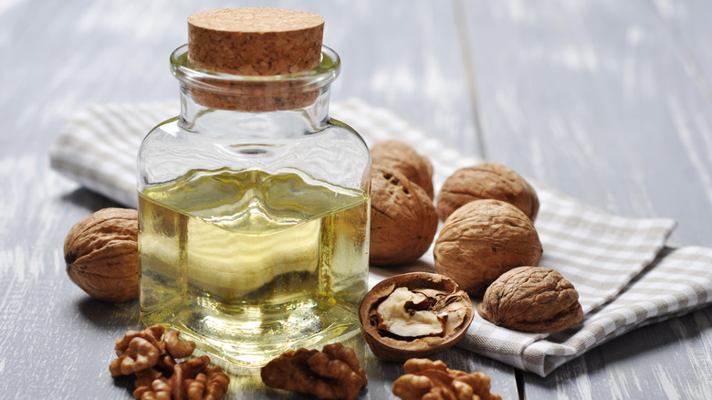 glass jar of walnut oil near walnuts