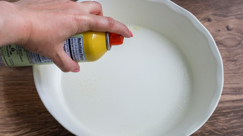 a pie pan being sprayed with nonstick spray