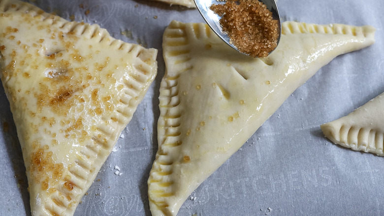 spoon sprinkling sugar onto turnover