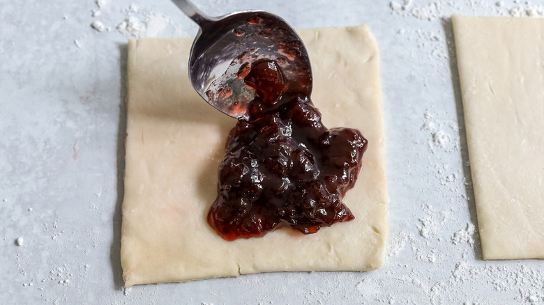 spoon placing jelly on pastry