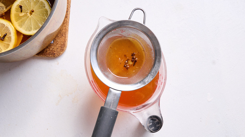 cloves straining in orange liquid