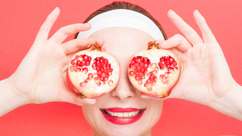 Woman holding pomegranates up to eyes