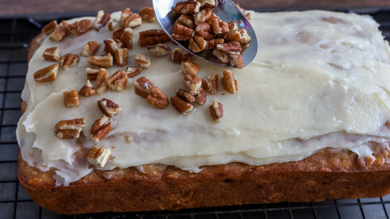 pecans being spooned onto frosting