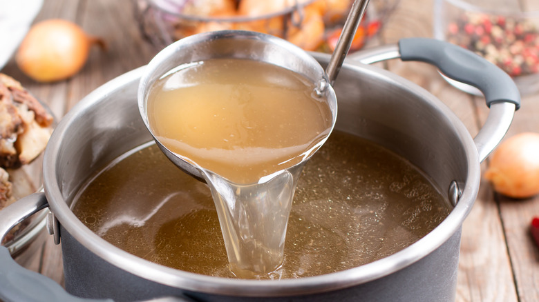 Ladle holding beef stock