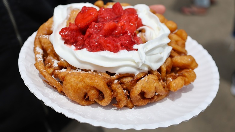 Funnel cake topped with whipped cream and strawberries