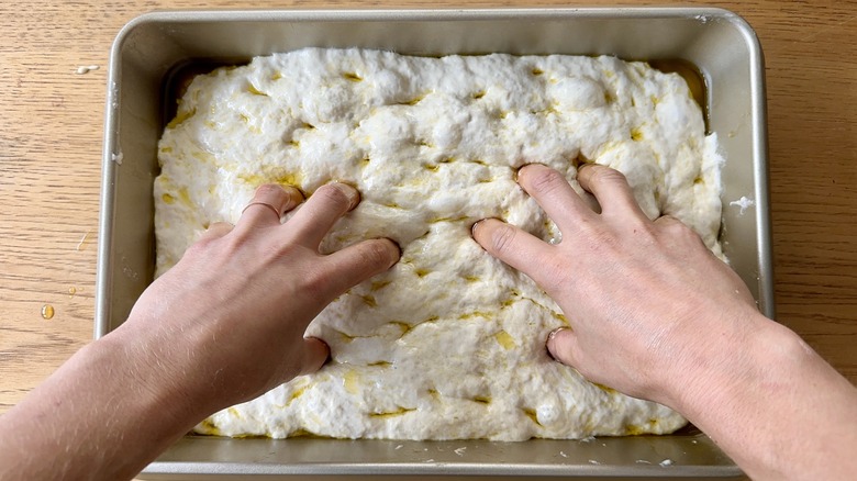 Dimpling focaccia with fingertips