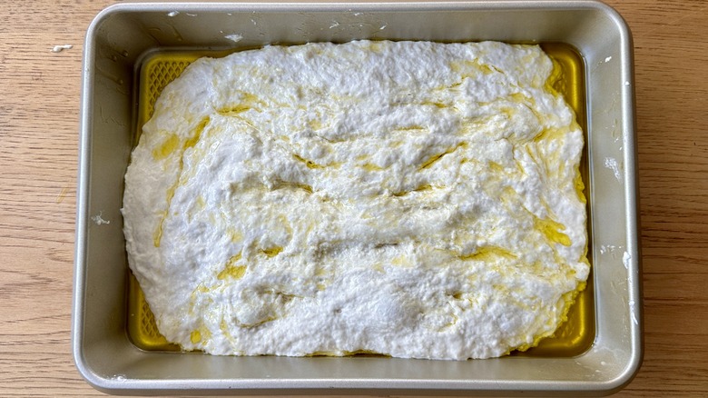 Stretched focaccia dough in pan