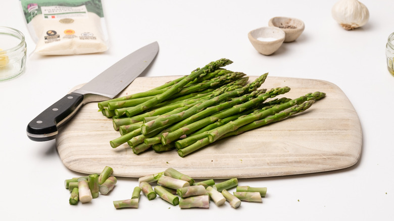 Knife and asparagus on cutting board