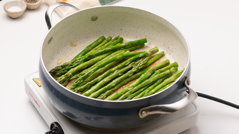 Asparagus spears frying in pan