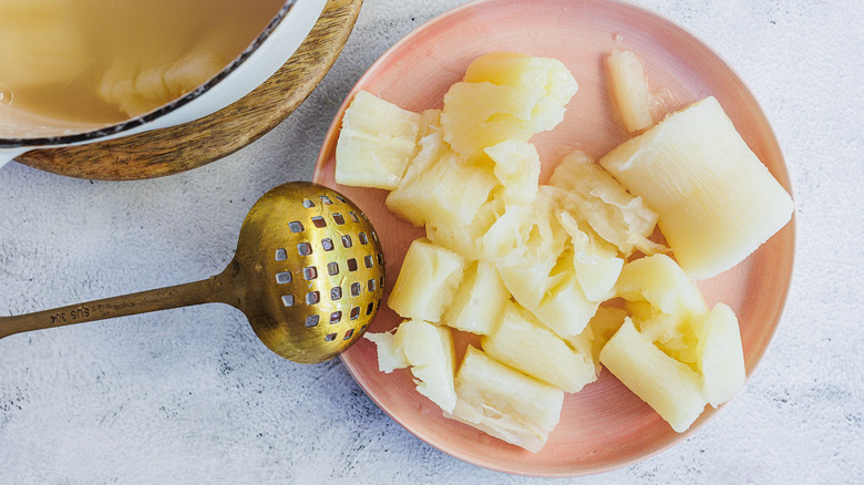 Boiled yuca in plate with pot and ladle