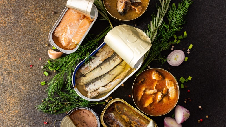 Open cans of fish surrounded by fresh herbs 