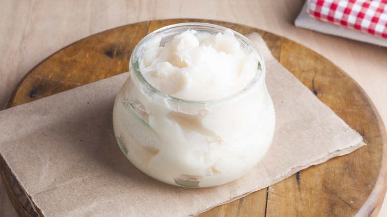 Glass jar of lard on wooden board 