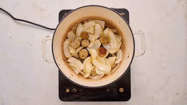 cooking sausage and onions in pot