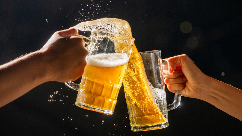 Two people clinking glass mugs of German beer