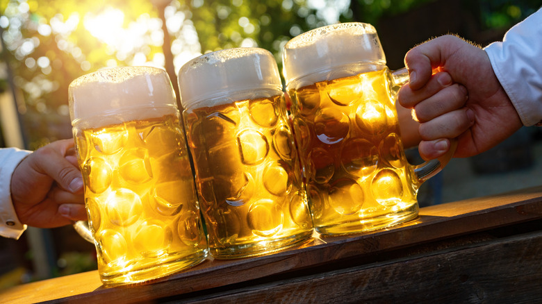 Hands holding Bavarian beer mugs