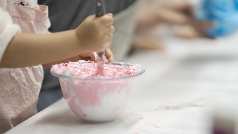 child stirring whipped cream