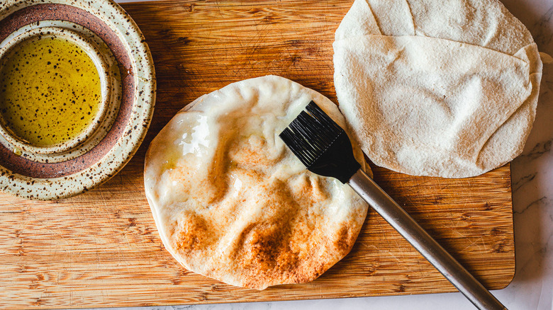 pitas and brush and olive oil on cutting board