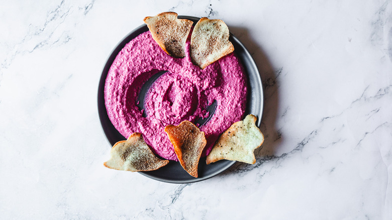 pink beet hummus and ghost shaped chips on black plate