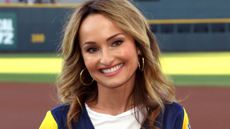 Giada de Laurenttis smiling with hoop earrings at baseball game