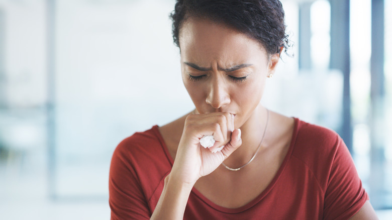 woman coughing with a tissue