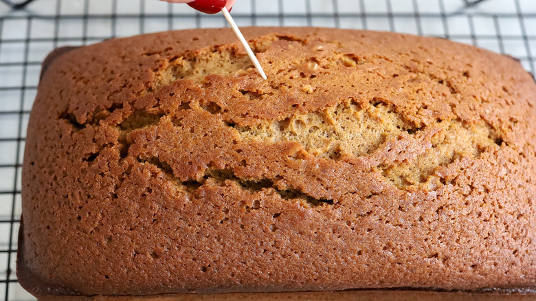 a gingerbread cake being poked with a toothpick