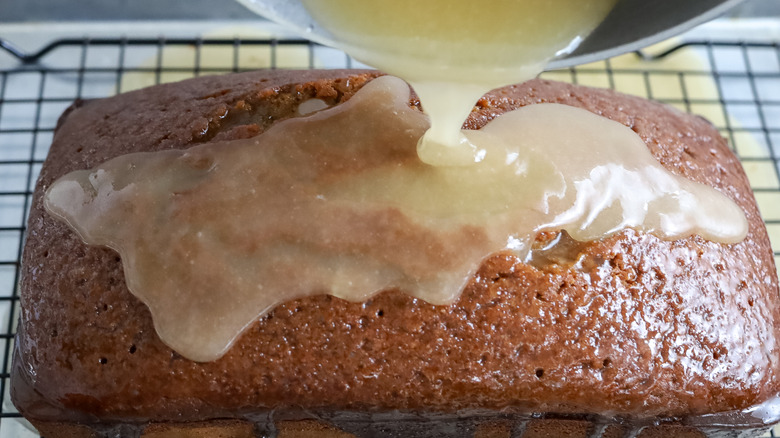 rum glaze being poured over a gingerbread pound cake