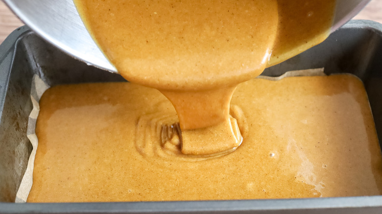 batter being poured into a loaf pan