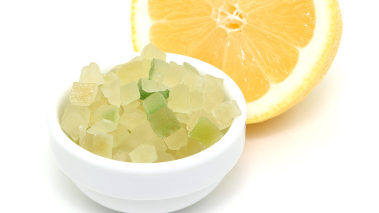 Small bowl of candied lemon peel in front of lemon slice