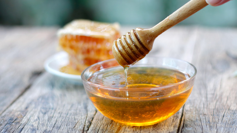 Small bowl of honey and wooden dipper