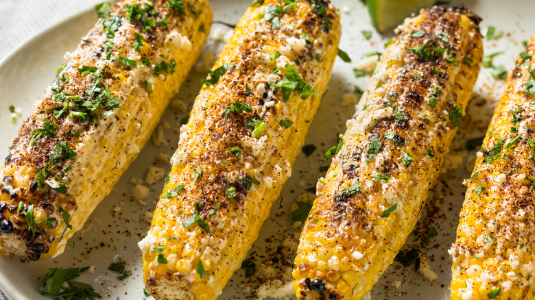 grilled ears of corn with crumbled cheese and chili powder